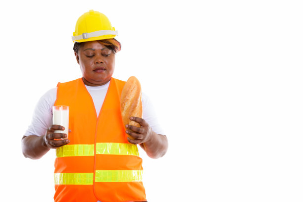 这是一名身材丰满的非洲黑人建筑女工拿着一杯牛奶，看着面包的照片图片下载