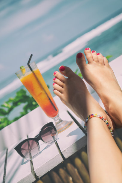 迷人的女孩在海滩上喝健康果汁。图片下载