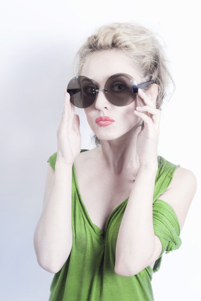 年轻美丽的女人在光的背景圆形太阳镜图片下载