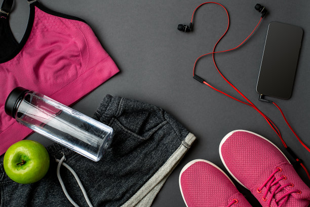 运动员的设置与女性服装，运动鞋和瓶装水在灰色的背景图片下载