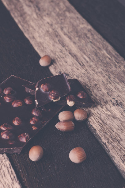巧克力块和榛子坚果在木背景。健美的照片。图片下载