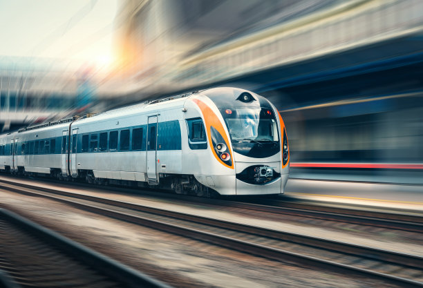 美丽的火车在日落时的火车站在欧洲。现代城际列车在铁路站台上的运动模糊效果。铁路上移动的客运列车的工业场景素材图片