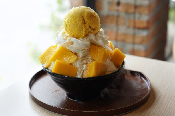 芒果刨冰，也被称为芒果冰苏韩国甜点，与糯米，鲜奶油和芒果冰淇淋一起放在桌子上。图片下载