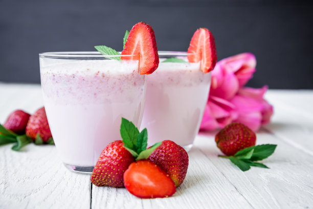草莓冰沙，草莓和花在白木背景。平的。前视图。新鲜的奶昔图片下载