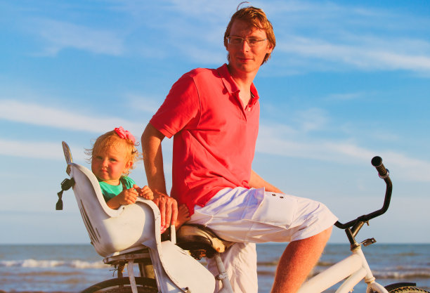 父亲和小女儿在海滩上骑自行车图片下载