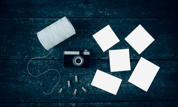 木桌上放着复古相机、空照片、晒衣夹和线轮。图片下载