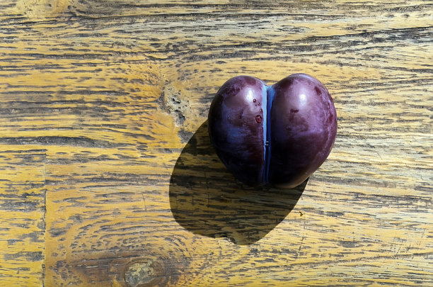 木桌上放着一对双生紫心梅子。从以上观点。图片下载