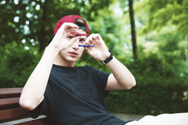 一个戴着帽子的长发嬉皮士坐在长凳上旋转指尖陀螺图片下载