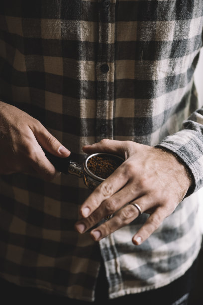 一步一步的煮咖啡的过程。男子正在进行咖啡梳理，夯实咖啡地面之前。图片下载