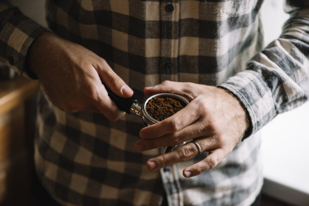 一步一步的煮咖啡的过程。男子正在进行咖啡梳理，夯实咖啡地面之前。图片下载