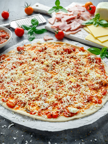 准备用蕃茄酱、芝士在羊皮纸上做披萨。图片下载