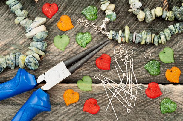 宝石，钳子和珠子创建手工珠宝在旧的木制背景。手工制作的配件。工艺产品图片下载