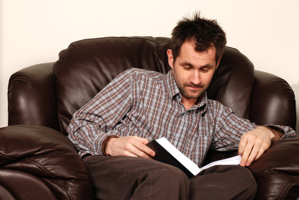 坐在扶手椅上看书的人图片下载