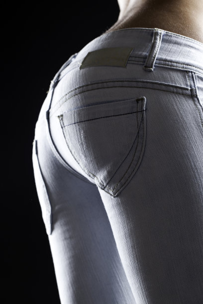 一个女人在蓝色牛仔裤黑色背景的完美躯干图片下载