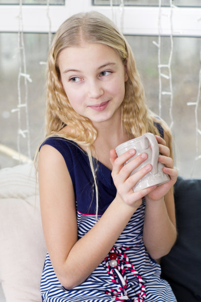 拿着杯子坐在窗边的年轻女孩图片下载