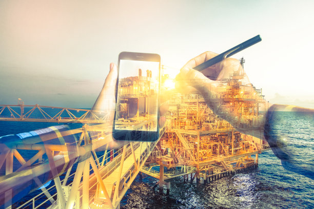 双重曝光炼油油气背景，和商人在潮人衬衫上用手机和电子笔进行油气经营理念。图片下载