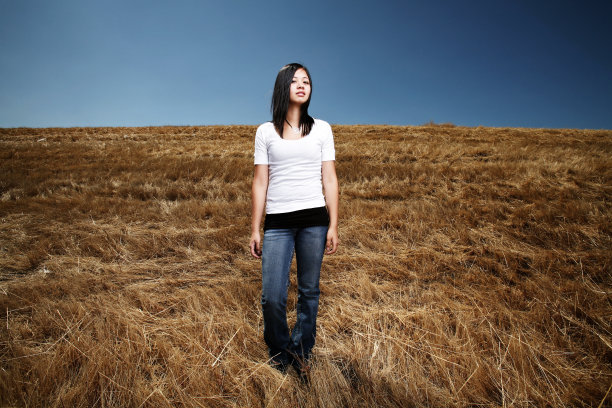 日落时分，年轻女子在广阔的田野里图片下载