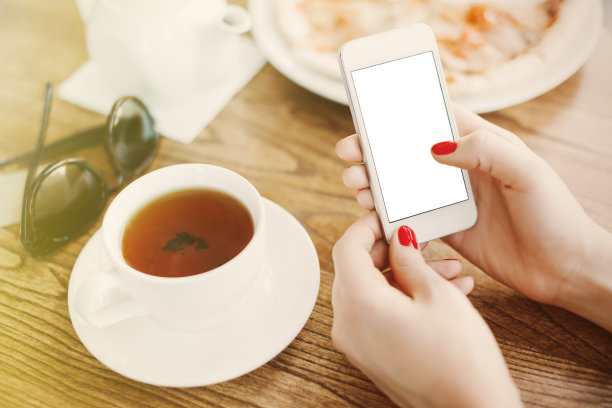一个女孩在咖啡馆拿着空屏幕的智能手机图片下载