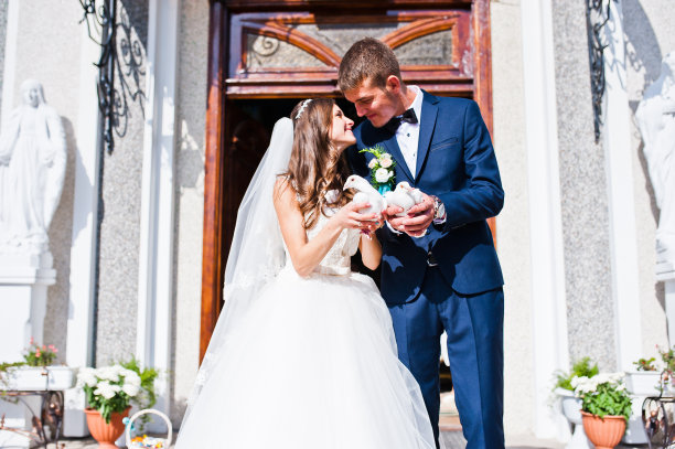 幸福的新婚夫妇和鸽子在教堂背景图片下载