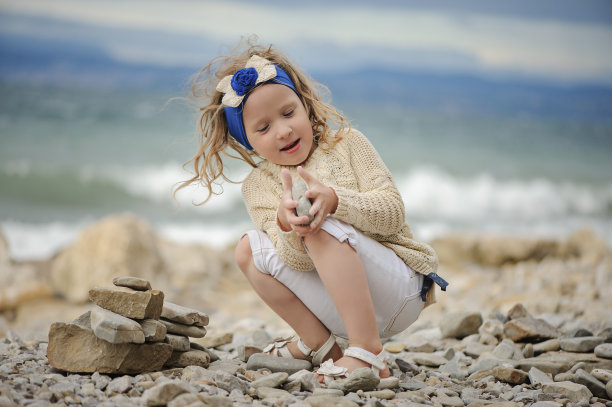 可爱的小女孩在海滩上建造石塔图片下载