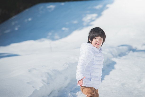 亚洲男孩在冬天的衣服与雪的背景图片下载