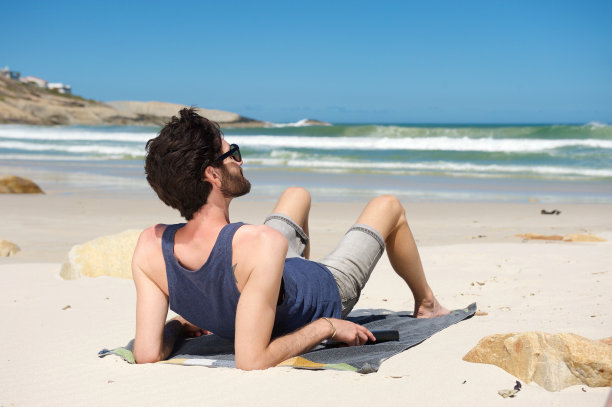 度假的年轻人独自坐在僻静的海滩上图片下载