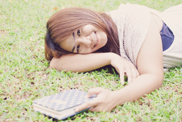 美丽的亚洲女人在花园里看书图片下载