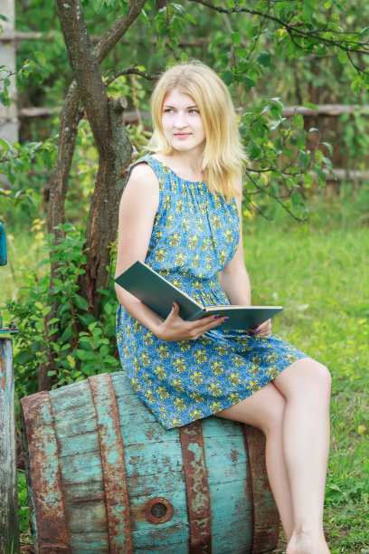金发女孩的肖像在女性丝绸连衣裙与书图片下载