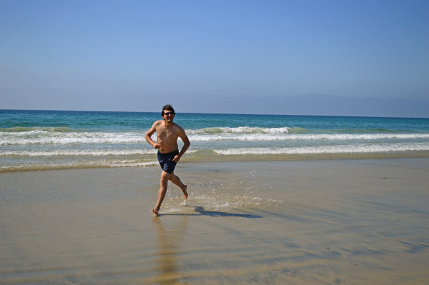 快乐的游客男子在海滩上跳高，享受在圣地亚哥，加利福尼亚，美国的假期图片下载