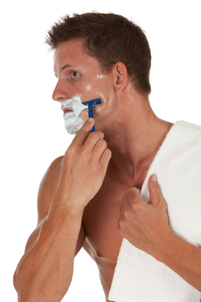 英俊的年轻人用剃须刀刮胡子图片下载