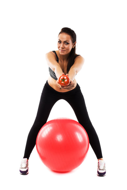 身材苗条的女孩拿着健身球递着番茄图片下载