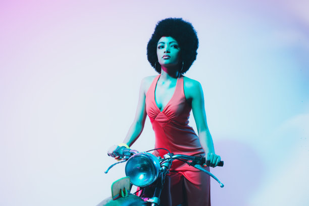 漂亮的年轻女人在她的摩托车上摆姿势图片下载