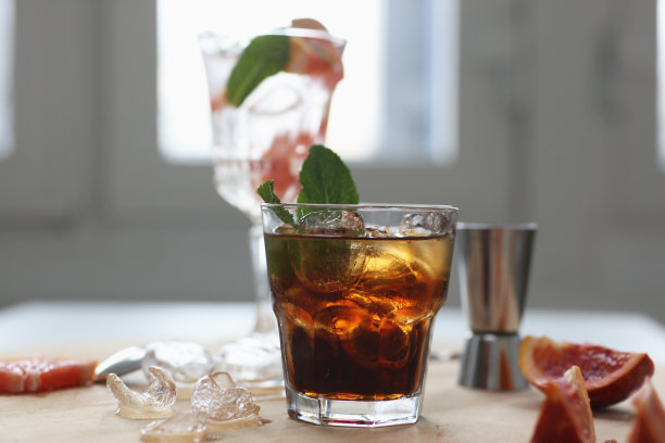 鸡尾酒威士忌可乐加冰在玻璃杯中。木板上放着水果的碎片。照片景深。图片下载