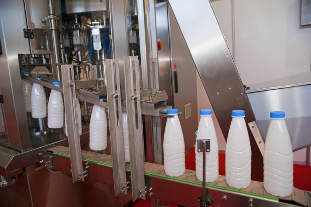 工厂传送带上的蓝盖塑料奶瓶图片下载