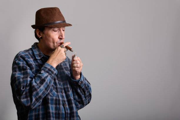 摄影棚里拍摄的一个成熟的黑帮男子在吸雪茄的时候点灯图片下载