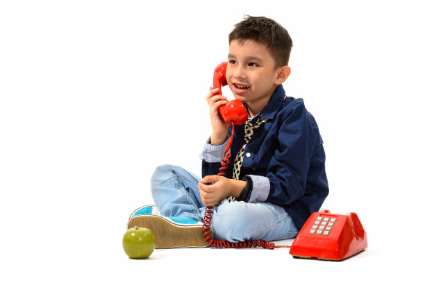 全身照片可爱的快乐的男孩微笑着和老电话聊天，而思考图片下载
