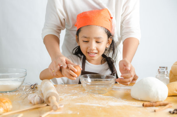 近距离拍摄的亚洲小女孩打破蛋壳做面包房图片下载