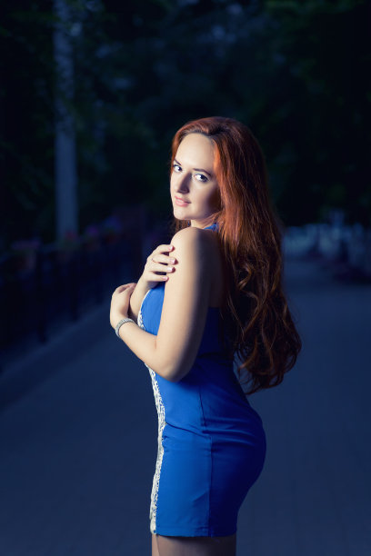 穿着蓝色衣服的年轻女子在夜晚的街道上摆姿势图片下载