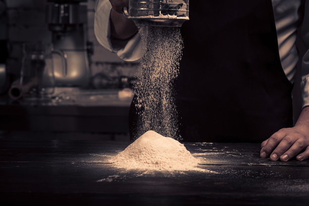 厨师的手正把面粉撒在一张木桌上图片下载