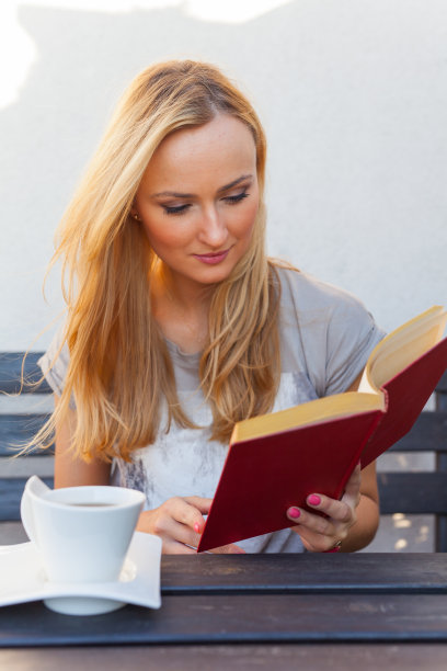 在门廊上看书喝咖啡的漂亮女人。户外的照片图片下载