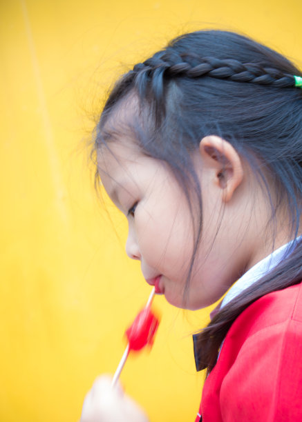 穿着红色衣服的小女孩吃着红色冰棒图片下载