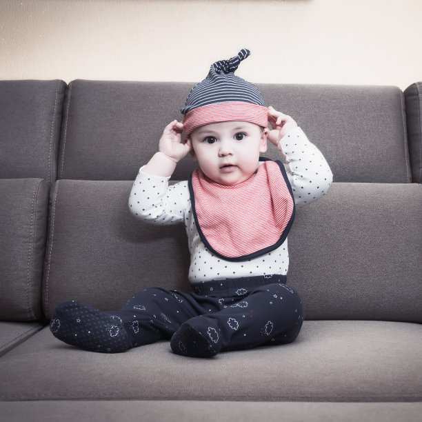 白人男婴戴着围嘴坐在家里的沙发上图片下载