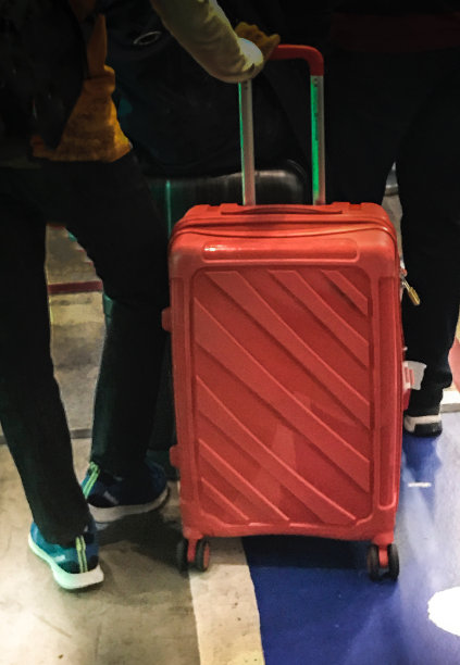 在机场拿着红色行李排队的男子图片下载