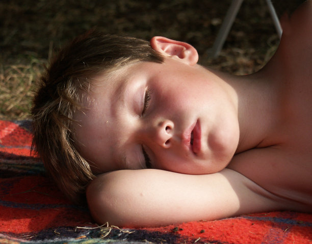 睡觉的男孩躺在阳光下的格子图片下载