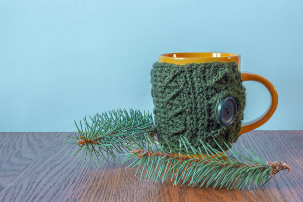编织封面的马克杯站在圣诞树旁图片下载