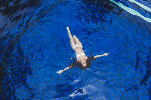 在巴厘岛的热带花园中，女人在深蓝色的水里放松。水疗有机皮肤护理，健康生活方式，热水浴缸图片下载