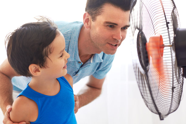 父亲和儿子在风扇前凉爽。炎热的一天图片下载