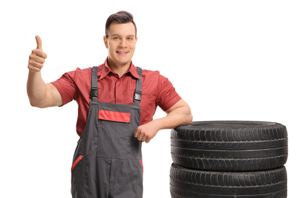 机械师靠在轮胎上，竖起大拇指图片下载