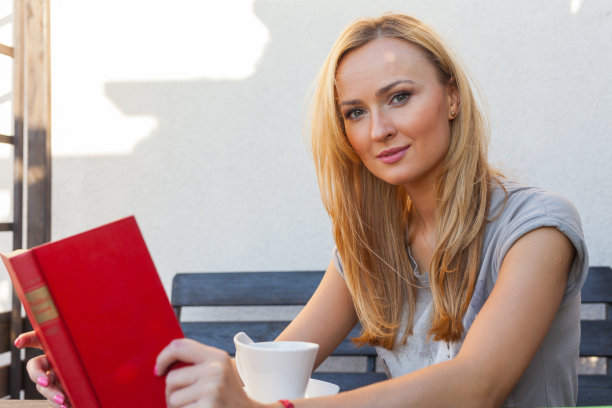 在门廊上看书喝咖啡的漂亮女人。户外的照片图片下载