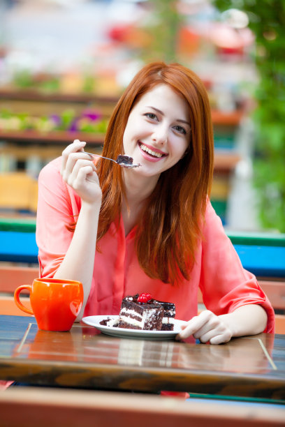 年轻美女在咖啡厅吃巧克力蛋糕的照片图片下载